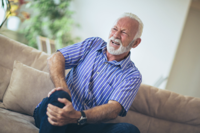 Older man clutching knee in pain or arthritis