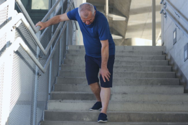 Man holding knee walking down steps