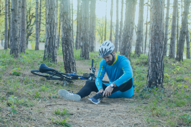 Man holding calf muscle beside bicycle