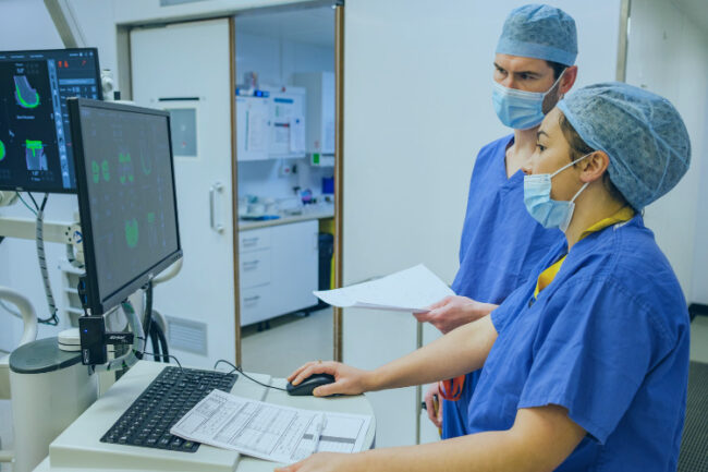 Mako robotic arm assisted surgeon Andrew Carrothers looking at screen with team