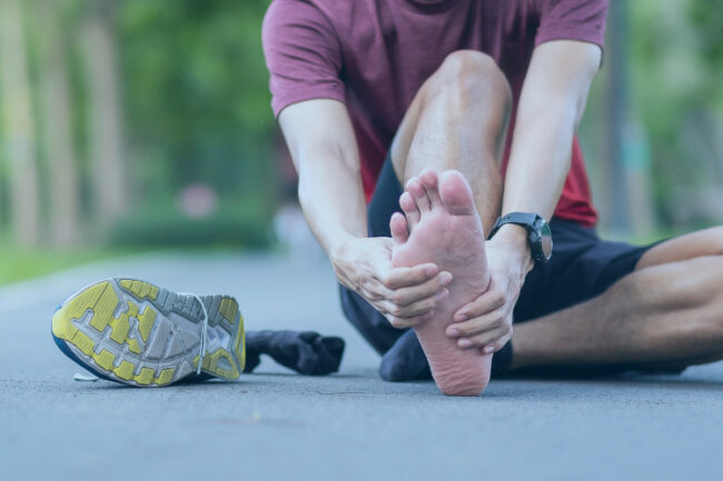 Sporty man holding foot in pain