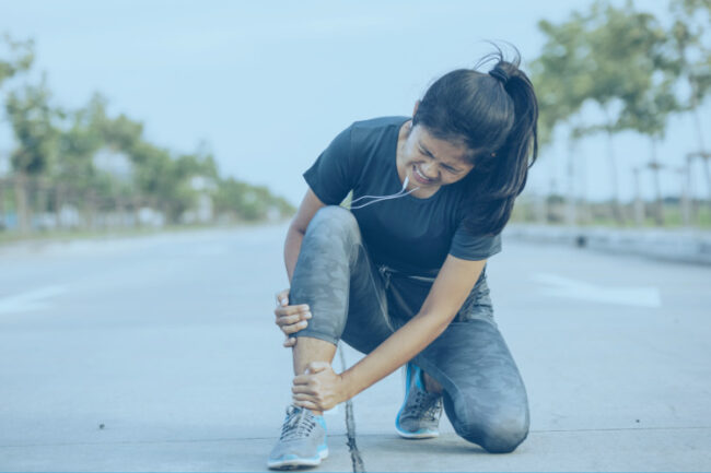 Sporty woman clutching ankle and shin in pain