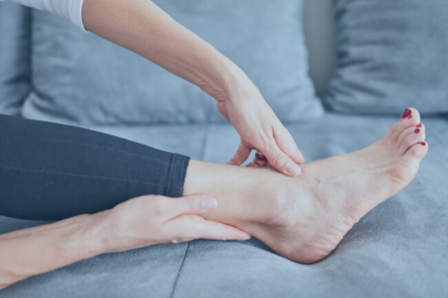 RICE treatment injuries Woman resting leg and ankle on sofa