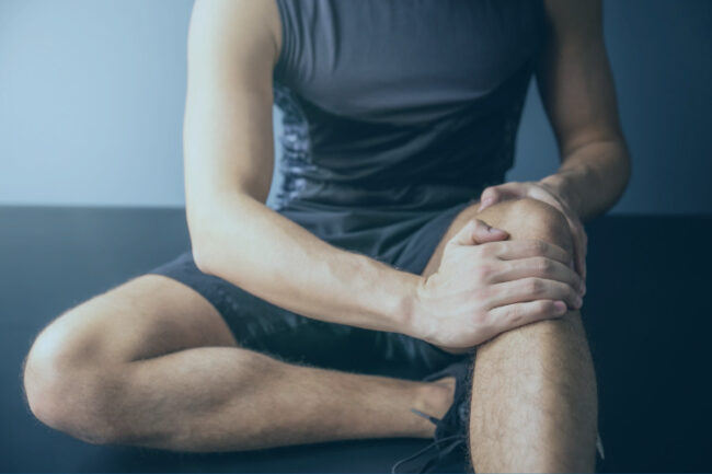 Sporty man on floor holding knee in pain