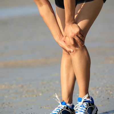 Woman running and holding knee in pain