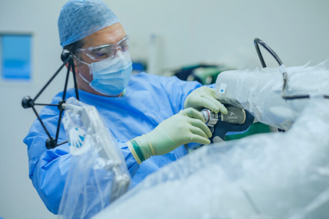 Surgeon using a mako robotic arm for joint replacement