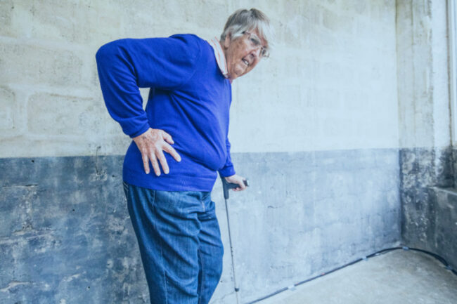 Older woman holding hip with pain from osteoarthritis