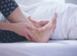 Woman holding her heel and foot in bed