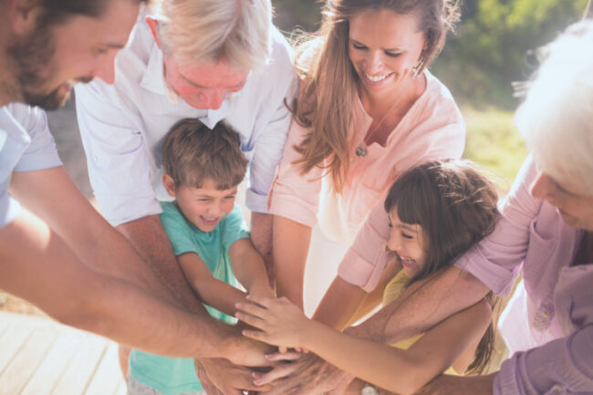 Exercising Tips for every decade of life Different generations outside with hands in a pile