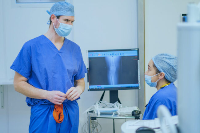 Andrew Carrothers discussing knee mako robotic assisted surgery image with colleague