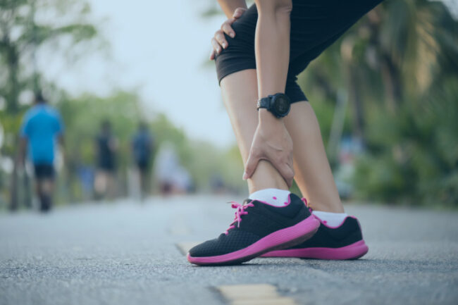 Woman runner holding ankle in pain