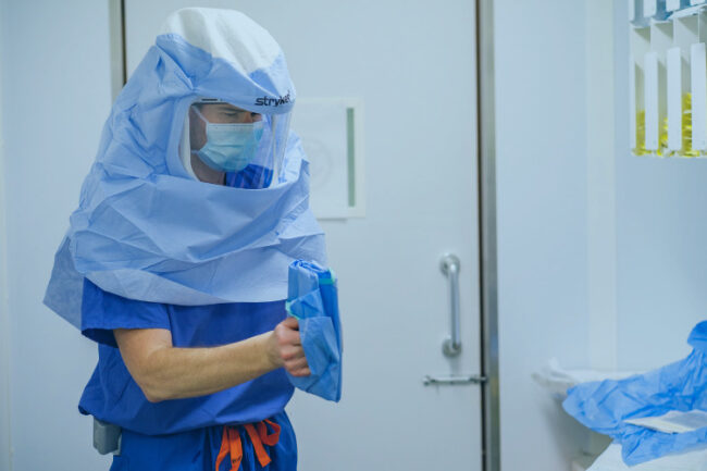 Treating Arthritis With Mako Total Hip Replacement Andrew Carrothers wearing a Stryker branded surgical clothing preparing for Mako Robotic Arm Assisted Hip Surgery