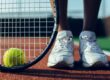 Tennis ball and racket with tennis players feet on the court