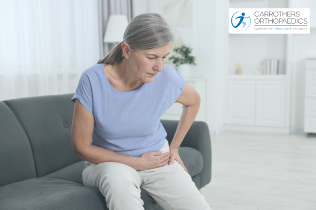 Woman on her sofa alone holding her arthritic hip in pain