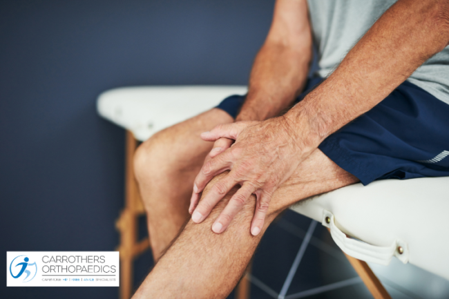 Man on doctor's bench holding knee