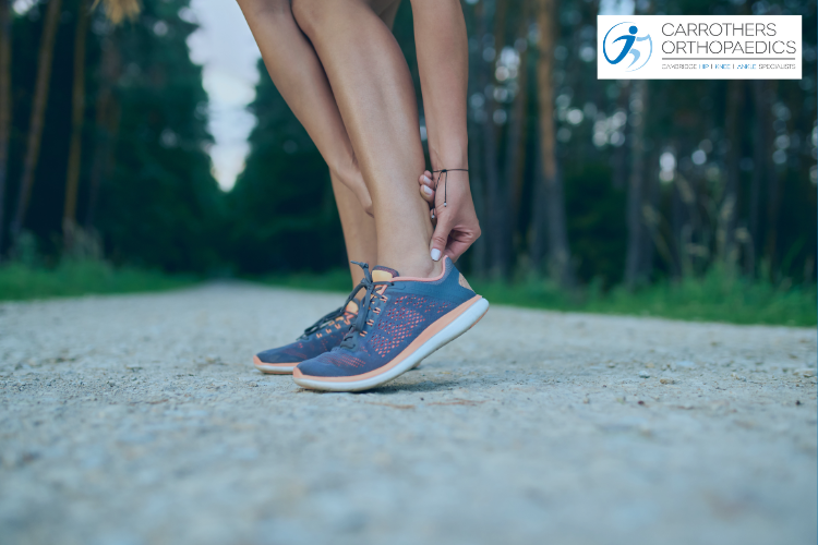 Sporty woman wearing trainers holding her Achilles tendon