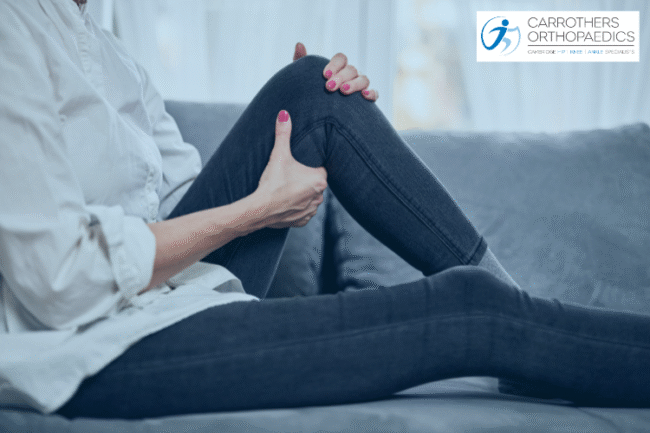 Woman sat on sofa holding her knee