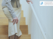 Older woman holding knee coming down stairs
