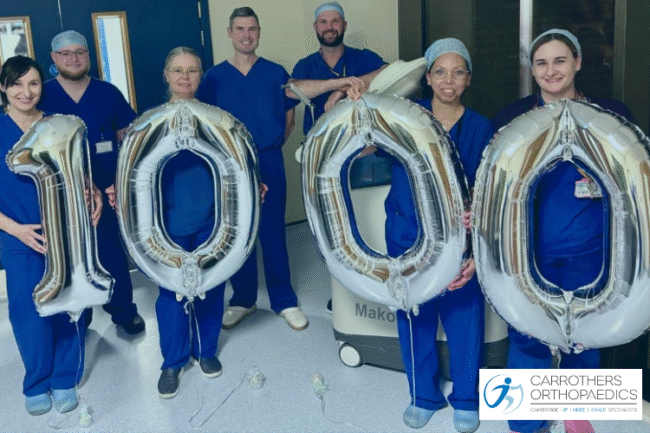 1000 Mako Robotic Arm Assisted Joint Replacements at Carrothers Orthopaedics Andrew Carrothers and the team with 1000 number on balloons