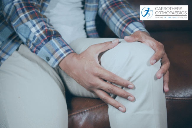 Man holding his knee sat on sofa