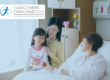 Older woman in a private hospital room with visitors sat on her bed
