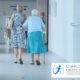 Older woman leaving hospital with a walking stick and family member